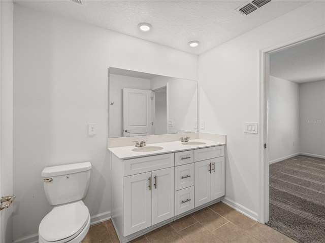 bathroom featuring vanity, toilet, and a textured ceiling