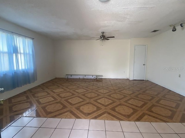 empty room featuring ceiling fan, tile patterned flooring, and a textured ceiling