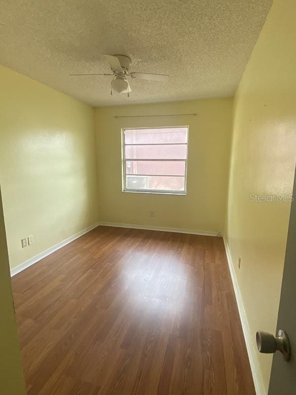 spare room featuring a textured ceiling, dark wood-type flooring, and ceiling fan