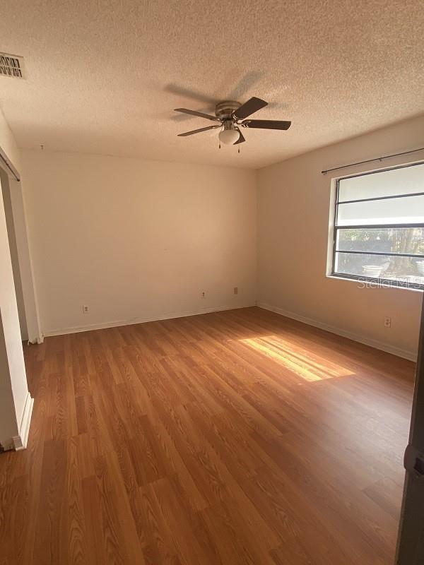 spare room with hardwood / wood-style floors, a textured ceiling, and ceiling fan