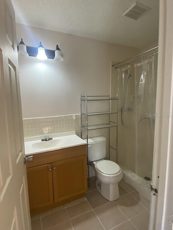 bathroom featuring tile patterned flooring, vanity, curtained shower, and a textured ceiling