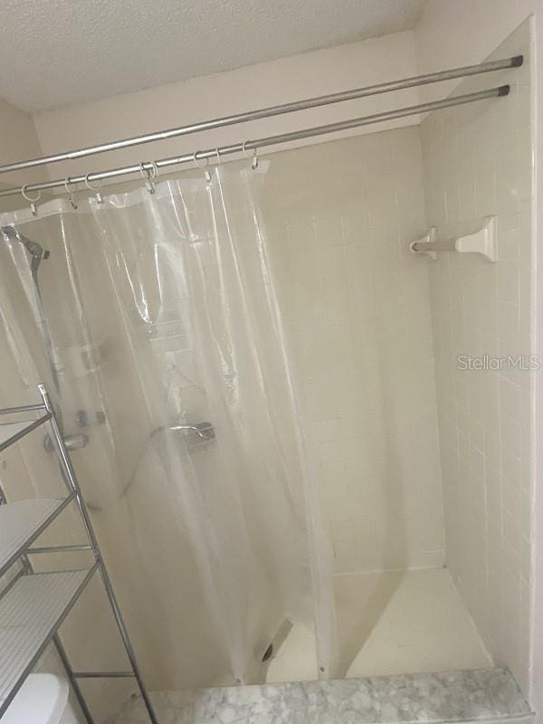 bathroom with a shower with shower curtain and a textured ceiling