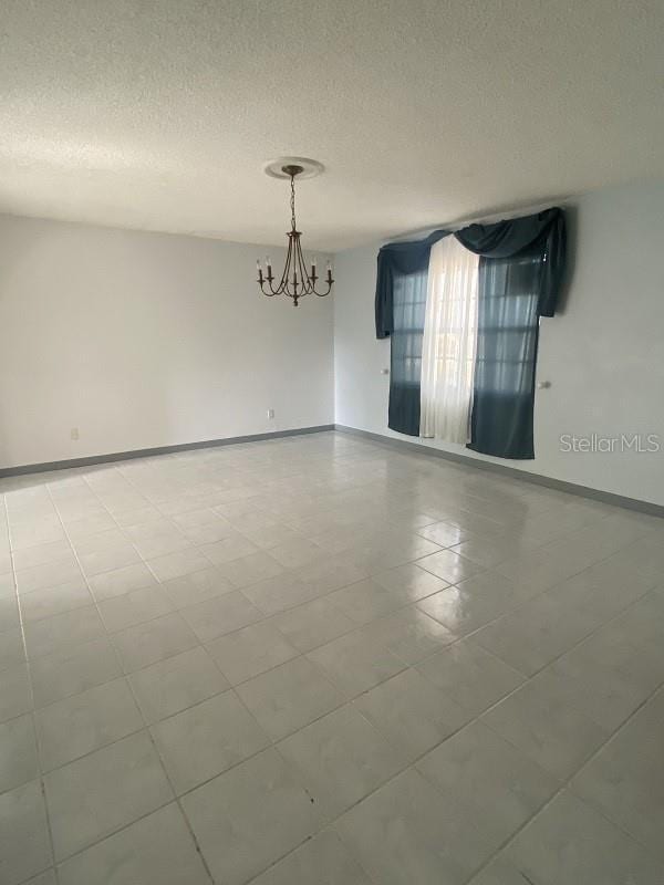 spare room with a notable chandelier and a textured ceiling