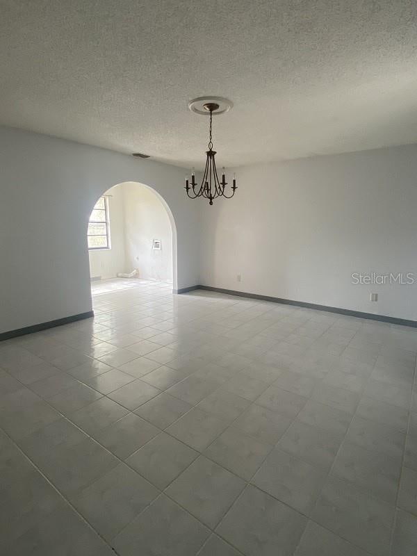 spare room featuring a notable chandelier and a textured ceiling