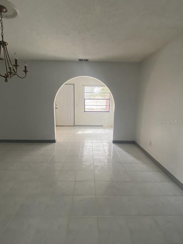 spare room with a notable chandelier and a textured ceiling