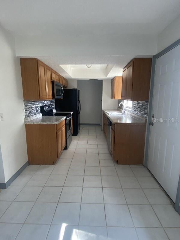 kitchen with tasteful backsplash, appliances with stainless steel finishes, sink, and light tile patterned floors