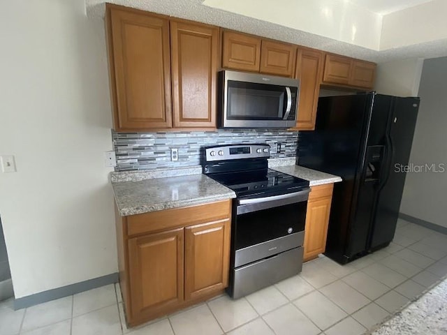 kitchen with backsplash, light tile patterned floors, and appliances with stainless steel finishes