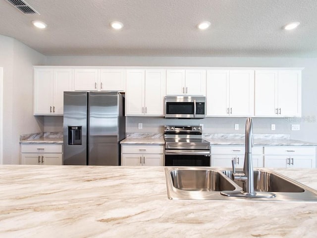 kitchen featuring sink, a textured ceiling, white cabinets, and appliances with stainless steel finishes