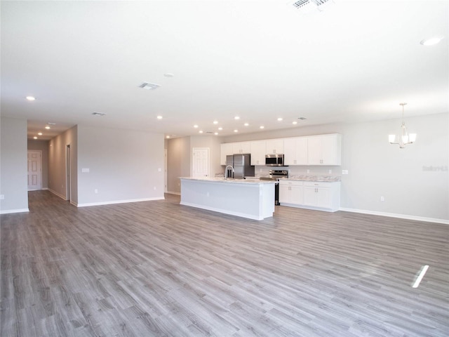 unfurnished living room featuring sink, light hardwood / wood-style floors, and a notable chandelier