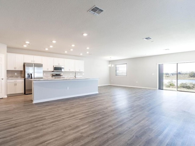 kitchen featuring a kitchen island with sink, hardwood / wood-style flooring, stainless steel appliances, and white cabinets