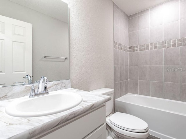 full bathroom featuring tiled shower / bath, vanity, and toilet