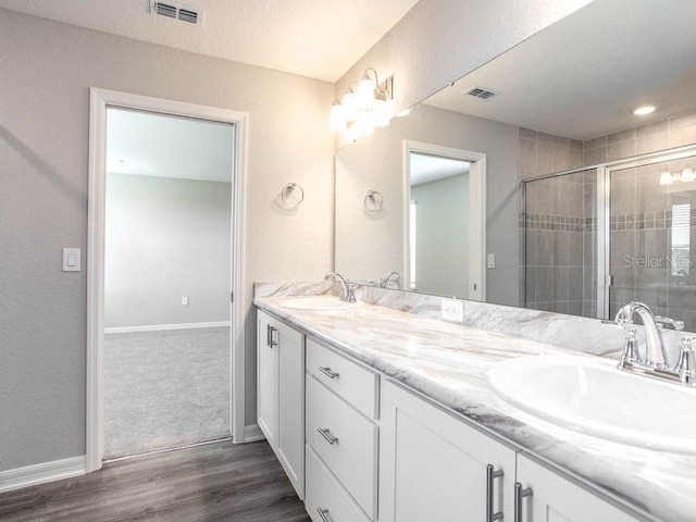 bathroom with vanity, hardwood / wood-style floors, an enclosed shower, and a textured ceiling