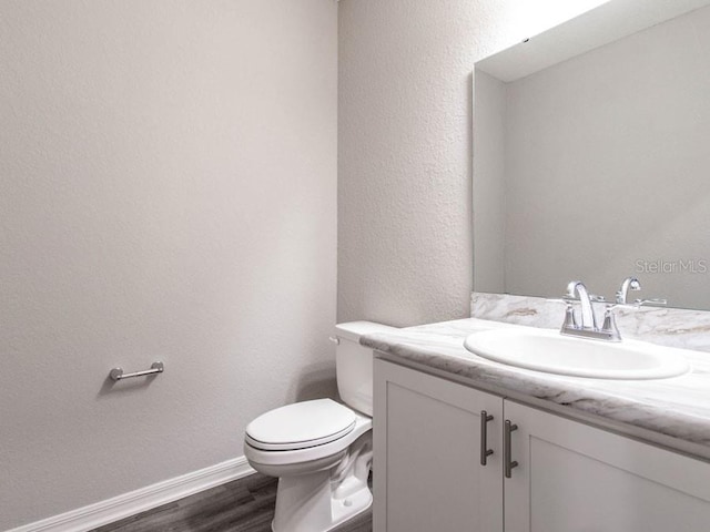 bathroom with vanity, toilet, and hardwood / wood-style floors