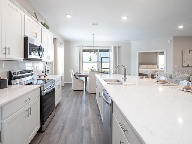 kitchen featuring sink, appliances with stainless steel finishes, dark hardwood / wood-style flooring, pendant lighting, and white cabinets