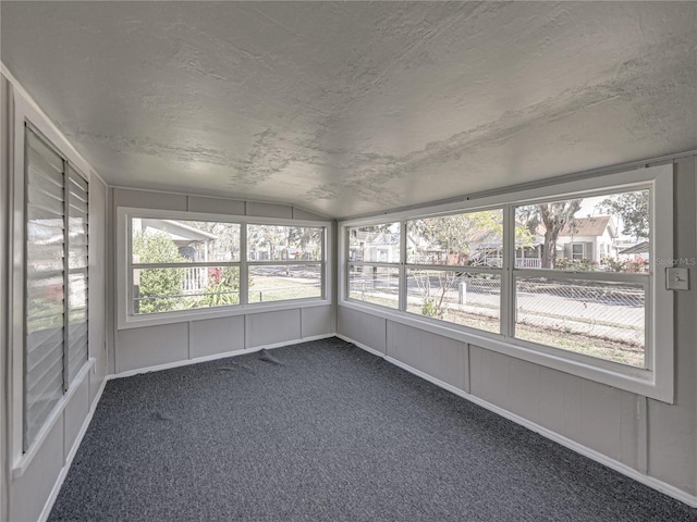 unfurnished sunroom featuring lofted ceiling and plenty of natural light