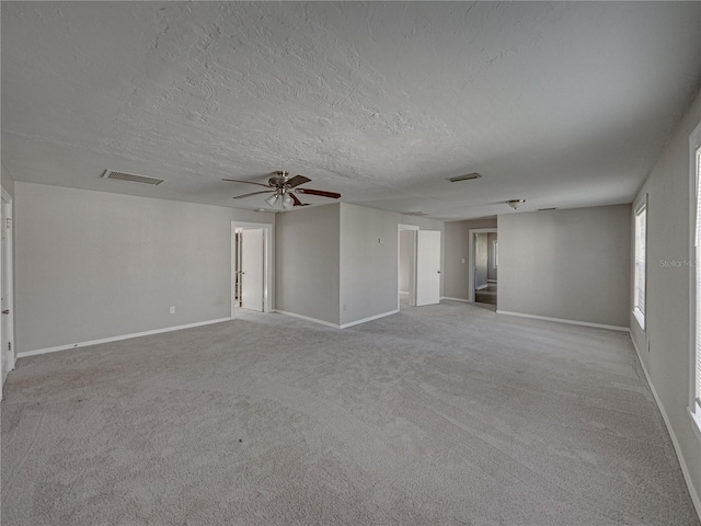 empty room featuring light carpet, ceiling fan, and a textured ceiling