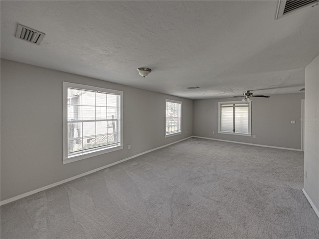 carpeted spare room featuring ceiling fan and a textured ceiling