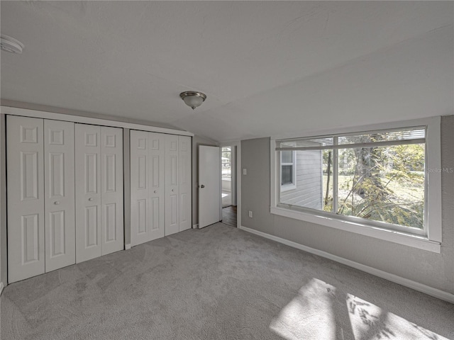 unfurnished bedroom featuring vaulted ceiling and light carpet