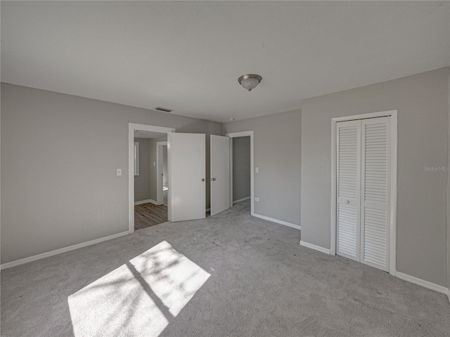 unfurnished bedroom featuring light colored carpet and a closet