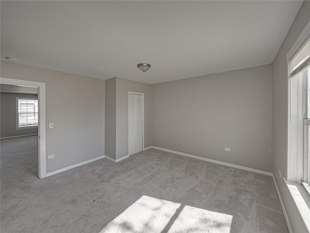 unfurnished bedroom with light colored carpet and a closet