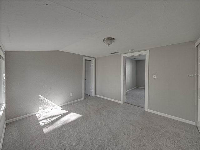 unfurnished bedroom featuring vaulted ceiling and light colored carpet