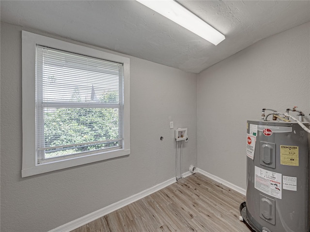 laundry area with electric water heater, washer hookup, a textured ceiling, and light hardwood / wood-style floors