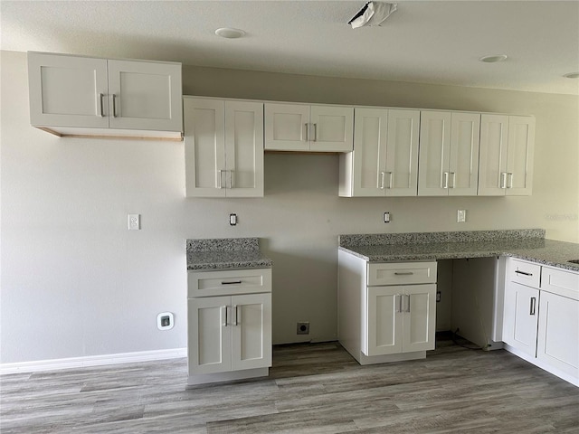 kitchen featuring white cabinetry, stone countertops, and light hardwood / wood-style flooring