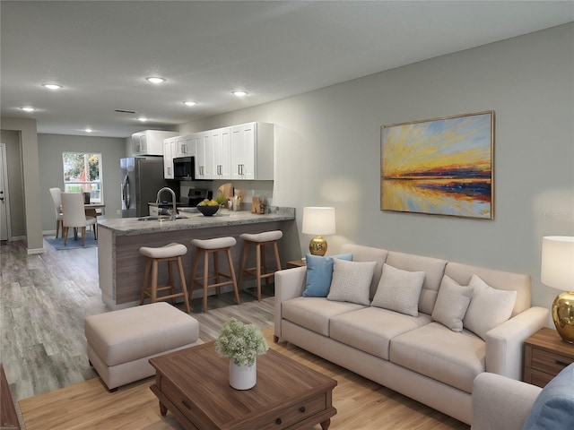 living area featuring recessed lighting, light wood-style flooring, and baseboards