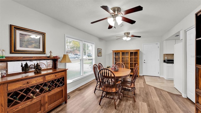 dining room featuring a textured ceiling, ceiling fan, and light hardwood / wood-style flooring