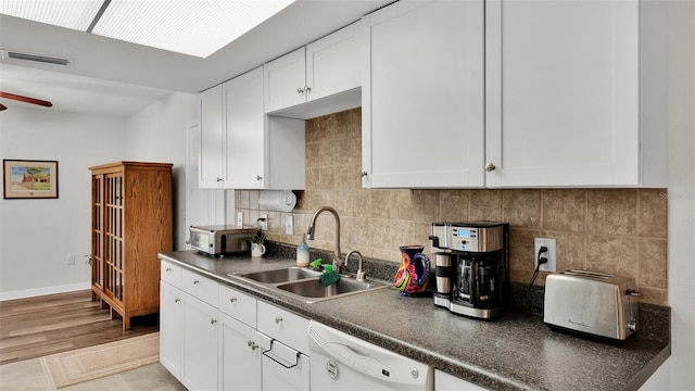 kitchen featuring tasteful backsplash, white cabinetry, sink, and white dishwasher