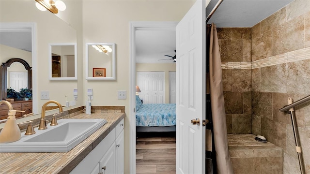 bathroom with walk in shower, ceiling fan, and vanity