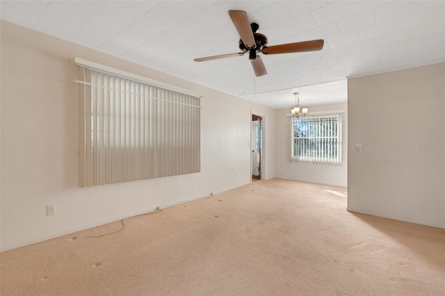 carpeted empty room featuring ceiling fan with notable chandelier