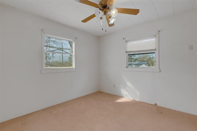 empty room with crown molding, a healthy amount of sunlight, ceiling fan, and carpet flooring