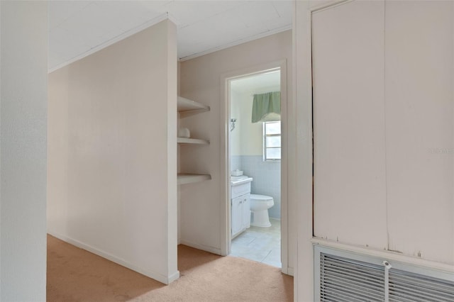 hall featuring light colored carpet and tile walls