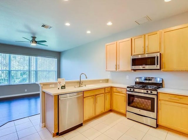 kitchen featuring light brown cabinetry, sink, kitchen peninsula, and appliances with stainless steel finishes