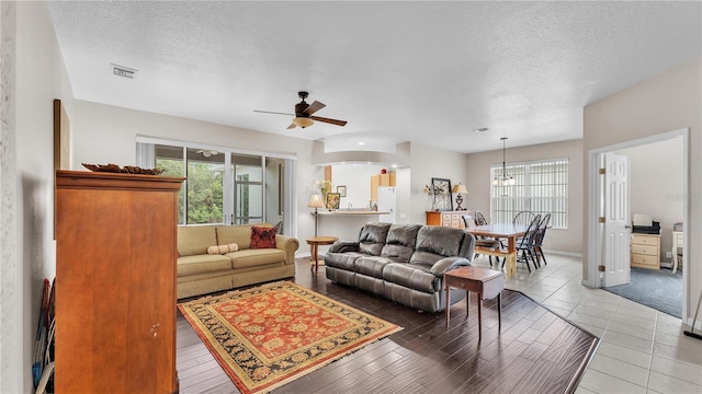 living room with a wealth of natural light, visible vents, and a textured ceiling