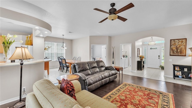 living area with ceiling fan with notable chandelier, wood finished floors, and baseboards