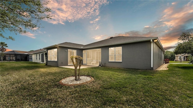 rear view of property with a yard, a patio, and stucco siding