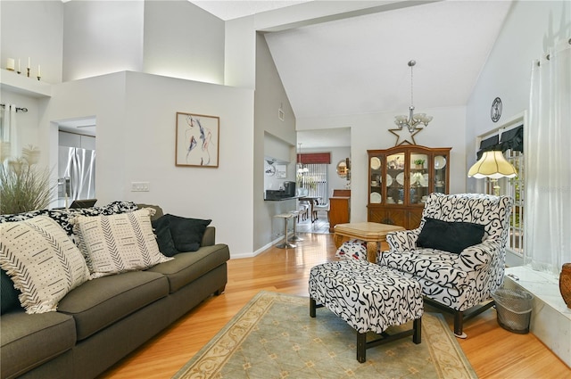 living room with high vaulted ceiling, a notable chandelier, and light wood-type flooring