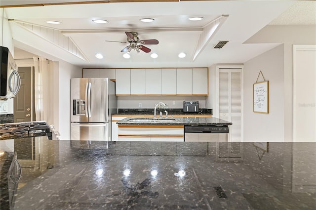 kitchen with white cabinetry, sink, dark stone counters, ceiling fan, and stainless steel appliances