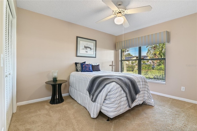 carpeted bedroom with ceiling fan and a textured ceiling