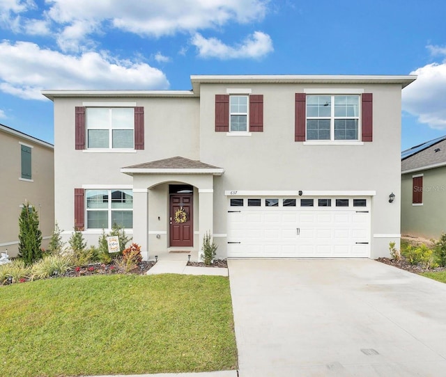 traditional-style house featuring concrete driveway, an attached garage, a front yard, and stucco siding