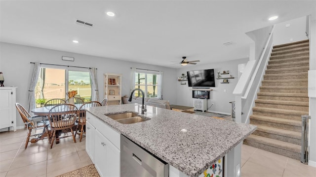 kitchen with sink, white cabinets, a kitchen island with sink, stainless steel dishwasher, and light stone counters