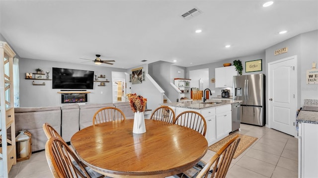 tiled dining room with ceiling fan and sink