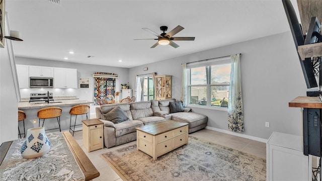 living room with sink, light tile patterned floors, and ceiling fan