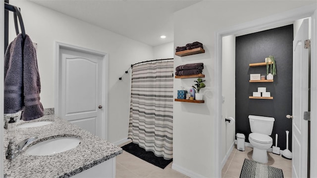 bathroom with tile patterned flooring, vanity, toilet, and walk in shower