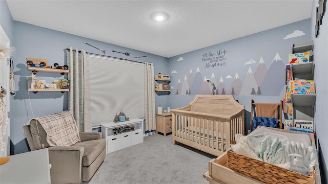 bedroom featuring a nursery area, carpet flooring, and a textured ceiling