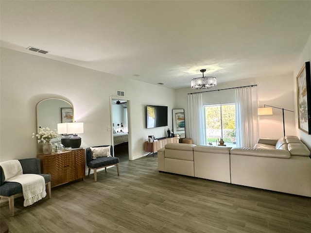 living room with dark hardwood / wood-style floors and an inviting chandelier