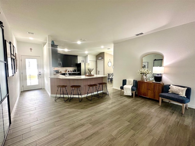 kitchen with a breakfast bar, stainless steel appliances, kitchen peninsula, and wood-type flooring