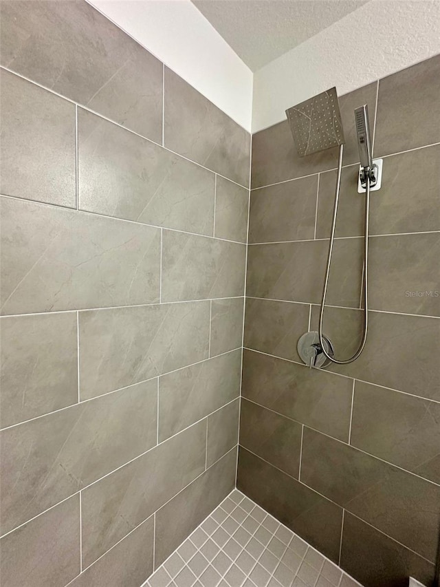 bathroom featuring a textured ceiling and a tile shower